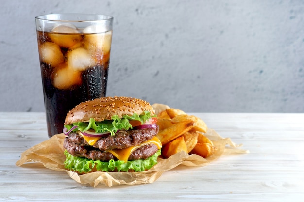 Zdjęcie podwójny cheeseburger ze smażonymi ziemniakami i szklanką coli