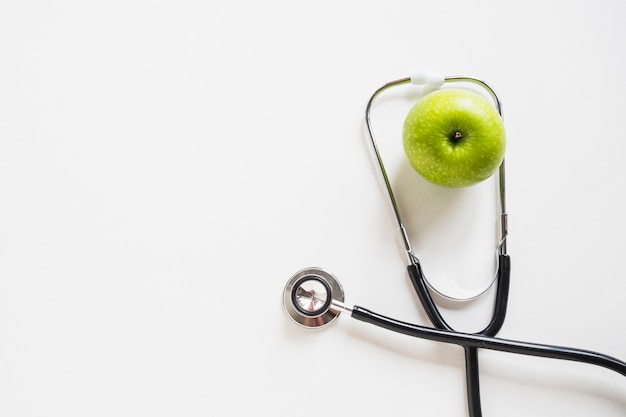 Zdjęcie podwyższony widok zielony jabłko z stetoskopem na białym tle