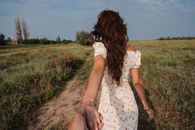 Pójdź za mną Młoda kaukaska kobieta trzymająca się za rękę i prowadząca podróżnika w malowniczym stepowym bezkresnym krajobrazie Jesień lub lato