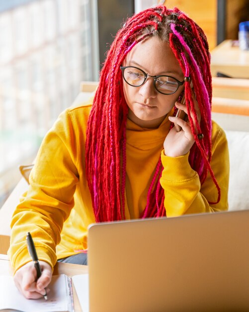 Pojęcie cyfrowego koczownika. Freelancer dziewczyna rozmawia przez telefon komórkowy, pracując zdalnie na laptopie