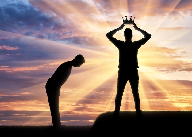 Zdjęcie pojęcie egoizmu i narcyzmu. sylwetka mężczyzny ubiera swoją koronę, a sługa kłania mu się