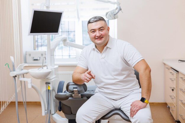 Pojęcie medycyny zawód stomatologia i medycyna uśmiechnięty dentysta w średnim wieku na tle gabinetu lekarskiego Dentysta jest w swoim gabinecie stomatologicznym