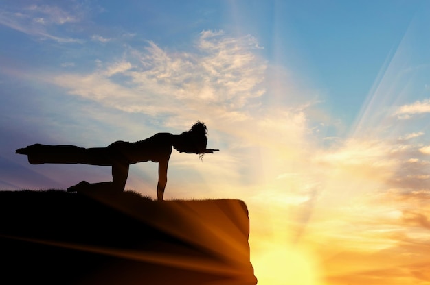 Pojęcie medytacji i relaksu. Sylwetka dziewczyny ćwiczącej ćwiczenia jogi na tle zachodu słońca