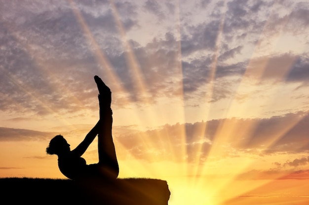 Pojęcie medytacji i relaksu. Sylwetka dziewczyny ćwiczącej ćwiczenia jogi na tle zachodu słońca