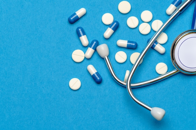 Pojęcie opieki zdrowotnej lub choroby - stetoskop i tabletki na niebieskim tle