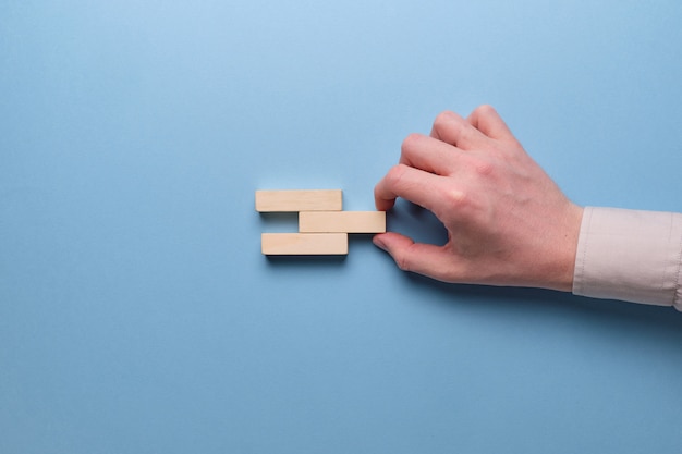Pojęcie optymalizacji biznesu. Ręka trzyma drewniane klocki na niebieskiej przestrzeni.
