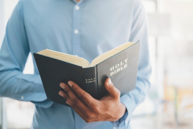 Pojęcie religii chrześcijaństwo. Mężczyzna trzyma i czyta świętą Biblię chrześcijańską.