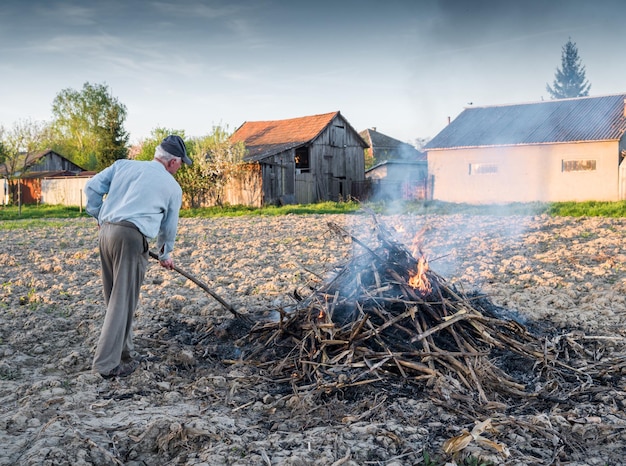 Zdjęcie pojęcie rolnictwa. praca w ogrodzie. rolnik spalający suszone gałęzie. wiosna
