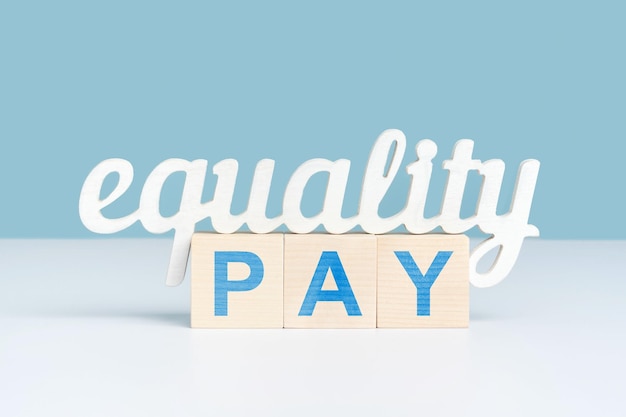 Pojęcie równej płacy słowo równość stoi na trzech drewnianych kostkach z napisem pay Zbliżenie