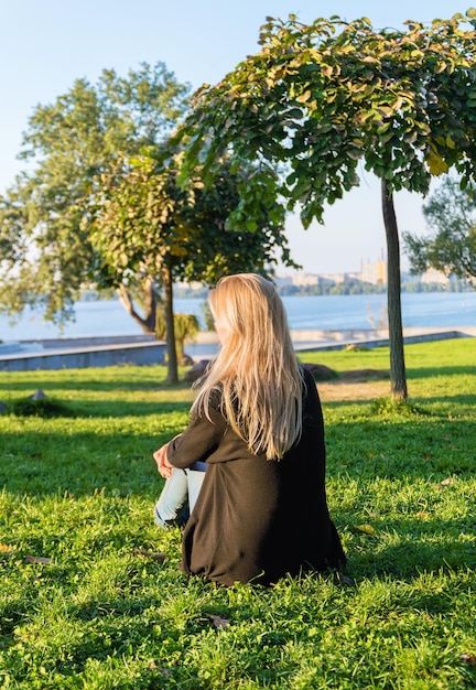 Pojęcie samotności i smutku. Samotna kobieta odpoczywa siedząc na trawie w parku