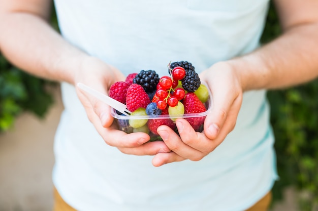 Pojęcie wegetarian, surowej żywności i diet - zbliżenie rąk człowieka trzymają owoce i jagody.