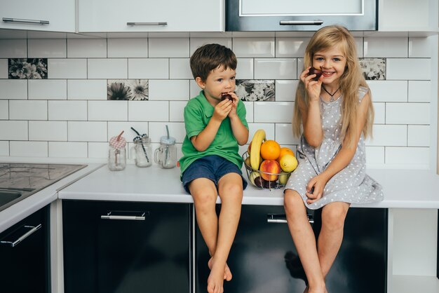 Pojęcie zdrowego odżywiania. śmieszne dzieci z owocami w kuchni