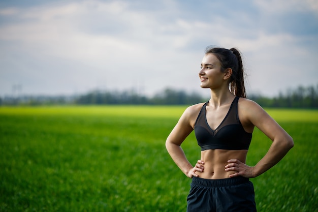 Pojęcie zdrowego stylu życia. Młoda atrakcyjna kobieta w sportowej sprawia, że rozciąganie ręki przed treningiem na łonie natury o świcie. Rozgrzewanie mięśni