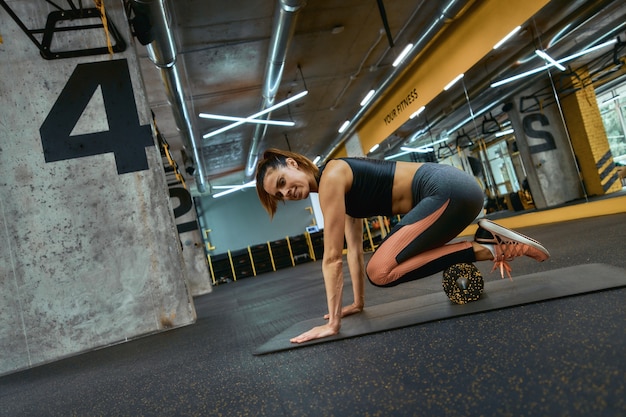 Zdjęcie pojęcie zdrowego stylu życia. młoda piękna kobieta sportive w sportowej, ćwiczenia ze specjalnym sprzętem fitness na siłowni, za pomocą wałka z pianki. sportowcy, koncepcja treningu i treningu