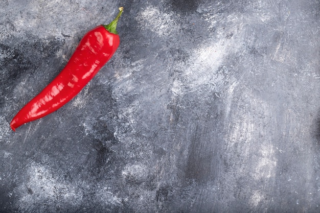 Pojedyncza organiczna papryczka chili umieszczona na marmurowej powierzchni.