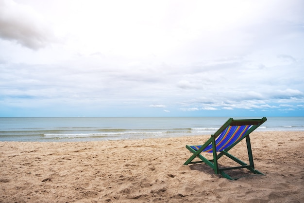 Pojedyncze krzesło plażowe nad morzem z niebieskim tłem nieba