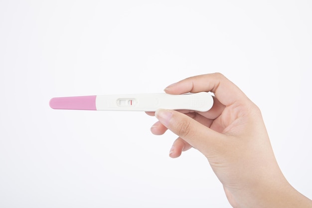 Zdjęcie pojedyncze ujęcie ręki trzymającej negatywny zestaw do testu ciążowego na białym tle