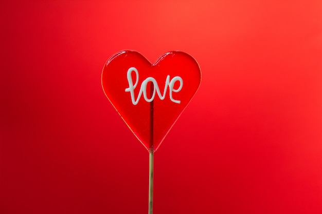 Pojedyncze w kształcie serca Lollipop z znakiem miłości na czerwonym tle