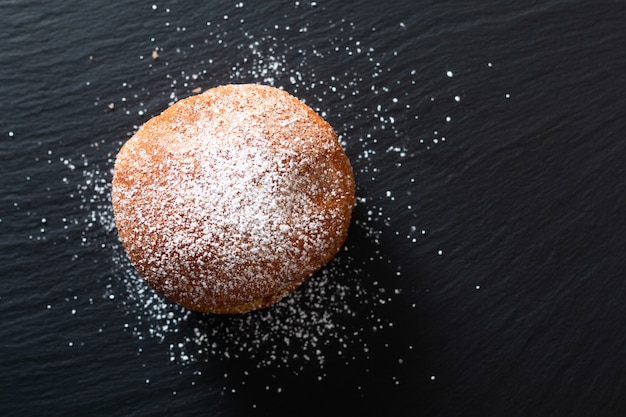 Zdjęcie pojedynczy koncepcja żywności beignet francuskie drożdżowe pączki drożdżowe smażone w głębokim tłuszczu na czarnej płycie łupkowej