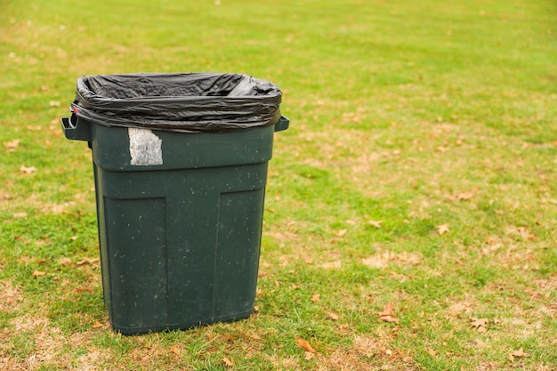 Zdjęcie pojemnik na śmieci pośród dziewiczego parku symbolizujący potrzebę odpowiedzialnego usuwania odpadów i środowiska