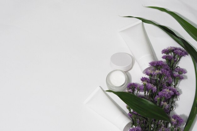 Zdjęcie pojemniki na butelki kosmetyczne biały produkt z kwiatkiem i liściem.