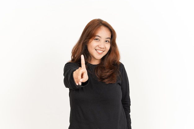 Pokazuje jeden palec pięknej azjatyckiej kobiety ubranej w czarną koszulę na białym tle