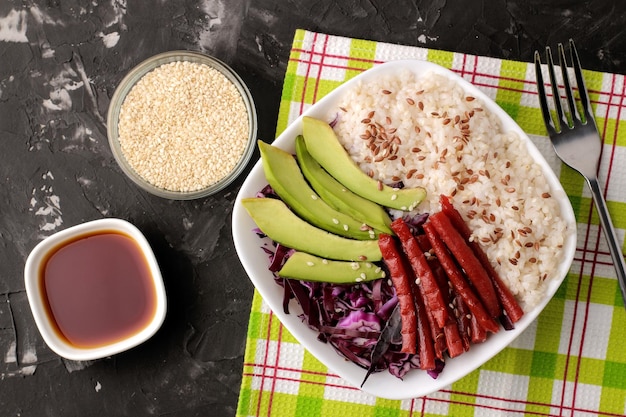 Poke bowl Hawajskie jedzenie talerz ryżowej kapusty łososiowej awokado i sera w pobliżu skunksa i sosu sojowego na czarnym tle widok z góry