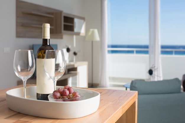 Pokój wakacyjny z widokiem na morze i stołem z butelką wina i kieliszkami.