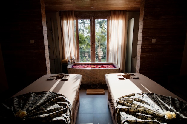 Zdjęcie pokój z dwoma stołami do masażu i oknem, przez które świeci słońce.