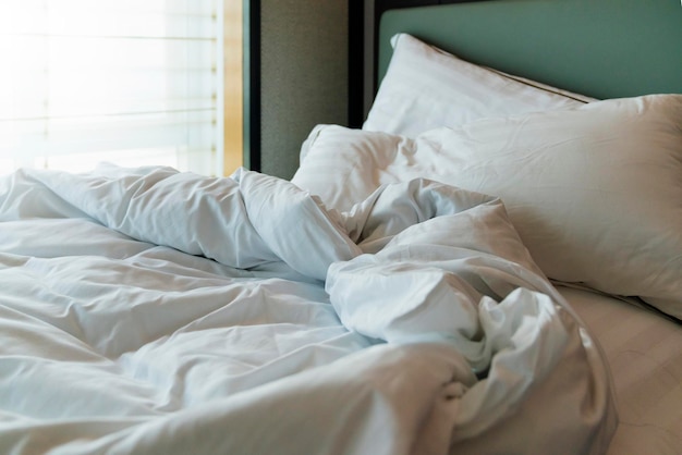Pokojówka z czystymi białymi poduszkami i prześcieradłami w pokoju kosmetycznym Zbliżenie Soczewka w świetle słonecznymWykręcać prześcieradło rano po przebudzeniu