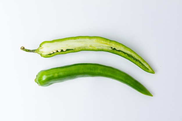 Pokrój na dwie zielone papryczki chili na białym tle