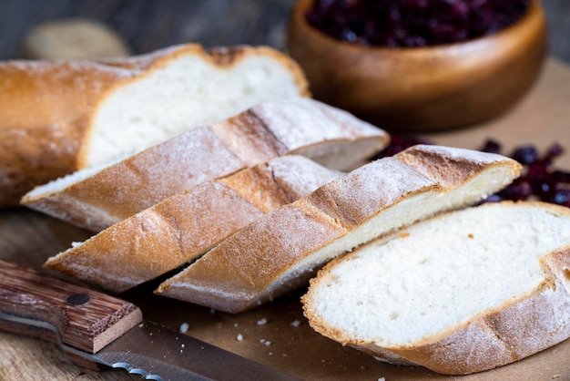 Pokrój świeżą bagietkę pszenną na kilka kawałków pokrojoną w plasterki miękką świeżą bagietkę na desce do krojenia i stole