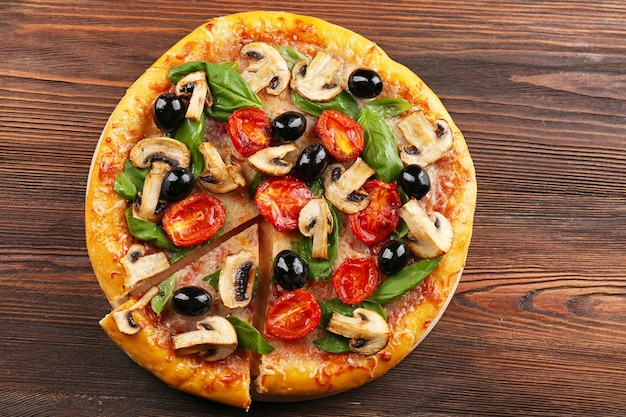 Pokrojona pyszna smaczna pizza z warzywami na drewnianym stole