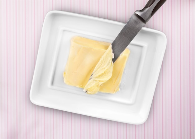 Pokrojone świeże loki masła w białym pojemniku na drewnianym stole