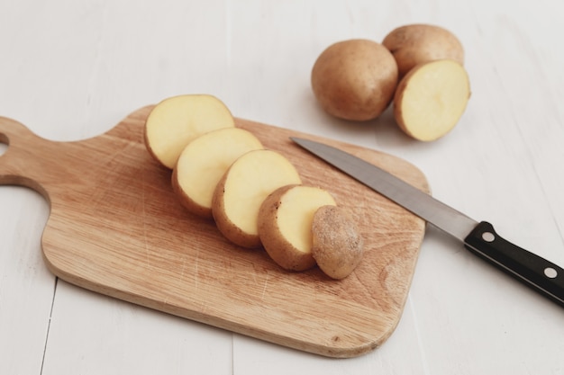 Pokrojone ziemniaki na stylu rustykalnym drewnianą deskę z nożem