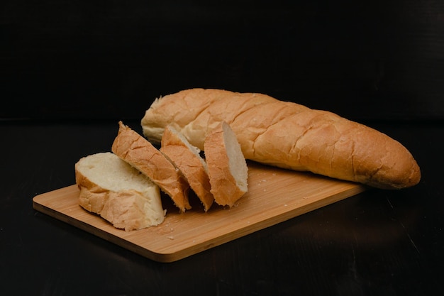 Pokrojony biały chleb leży na desce do krojenia na drewnianym tle