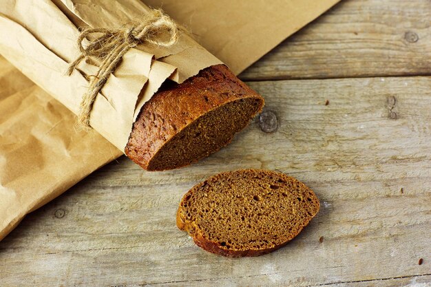 Pokrojony bochenek chleba zapakowany w papier na drewnianym stole