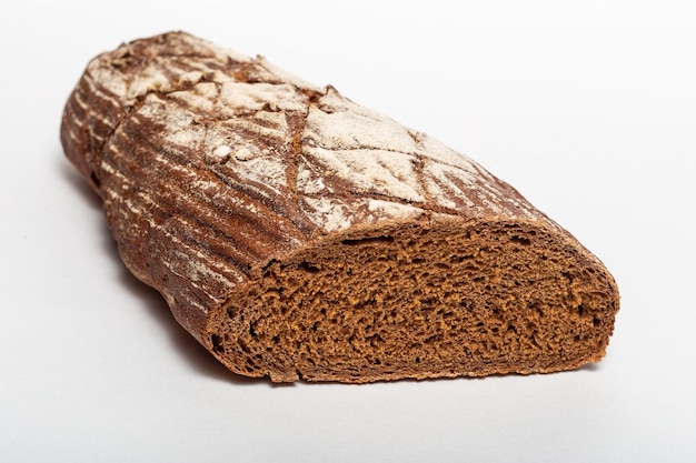 Pokrojony bochenek czarnego chleba żytniego z kawałkami od noża na wierzchu i posypane białą mąką na białym tle Zdrowe odżywianie koncepcja Zbliżenie widok boczny chleba
