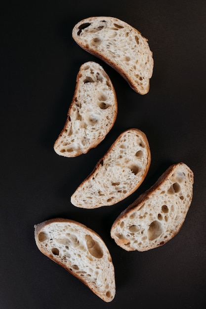 Pokrojony chleb ciabatta na czarnym tle. Włoski biały chleb. Widok z góry.