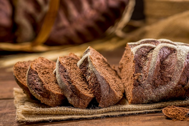 Pokrojony chleb z kakao i czekolady na rustykalnym suknem na rustykalnym drewnianym stole ze składnikami.