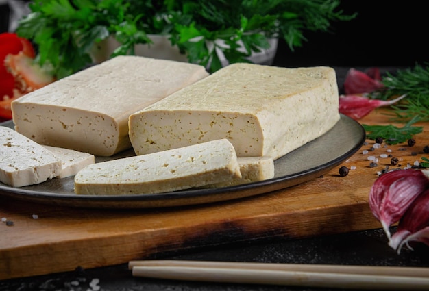 Pokrojony ser tofu sojowy na desce do krojenia z dodatkiem bazylii i warzyw