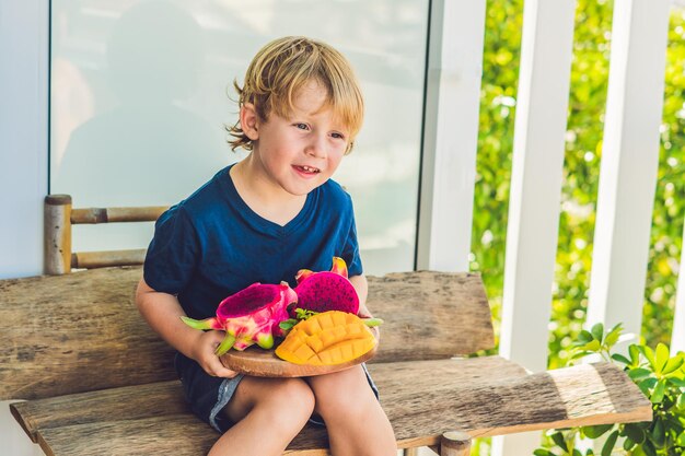 Pokrojony w kostkę smoczy owoc i mango w rękach chłopca