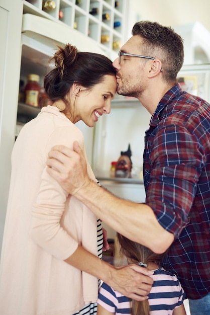 Połączeni miłością Ujęcie męża całującego żonę z rodziną w kuchni