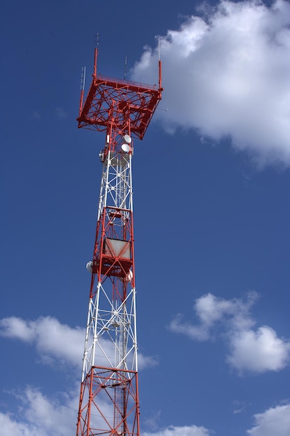 Połączenie wieży z masztem i antenami na tle błękitnego nieba z chmurami Transmisja i odbiór sygnałów