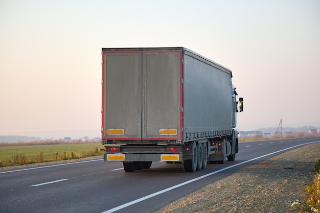 Półciężarówka z przyczepą towarową jeżdżącą po autostradzie, przewożącą towary wieczorem Dostawa koncepcja transportu i logistyki