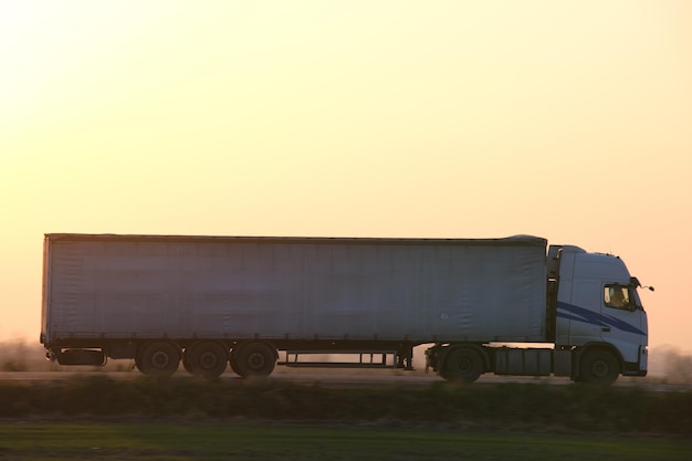 Półciężarówka z przyczepą towarową jeżdżącą po autostradzie, przewożącą towary wieczorem Dostawa koncepcja transportu i logistyki