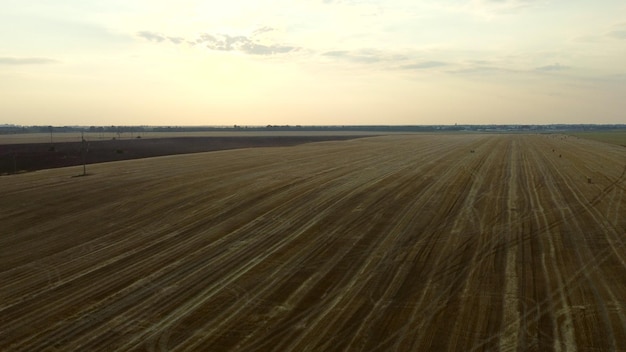 Pole po żniwach o zmierzchu kamera wznosi się niebo chmury