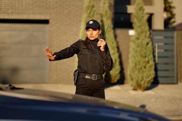 Zdjęcie policjant za pomocą walkie-talkie kontroli ruchu drogowego gestykulując zatrzymać samochód. egzekwowanie prawa