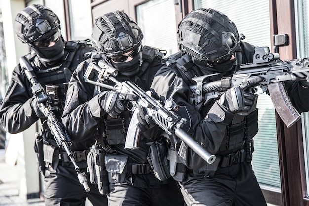 Policyjna jednostka taktyczna antyterrorystyczna, specjalna drużyna reakcyjna w czarnych pustych mundurach z ukrytą tożsamością, uzbrojona w karabiny szturmowe, poruszająca się w szyku podczas operacji reagowania na terroryzm