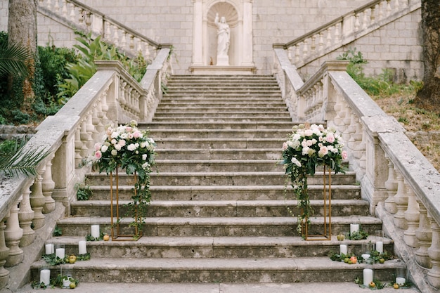 Półłucznik weselny z róż na cokołach stoi na kamiennych stopniach starożytnego kościoła